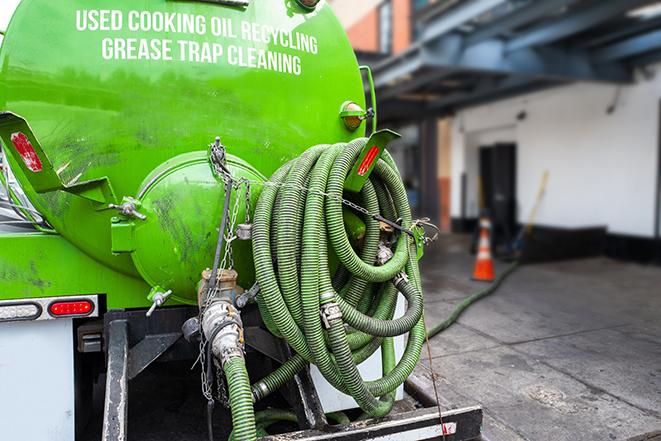 a professional plumber using a pump to empty a grease trap in Canoga Park, CA